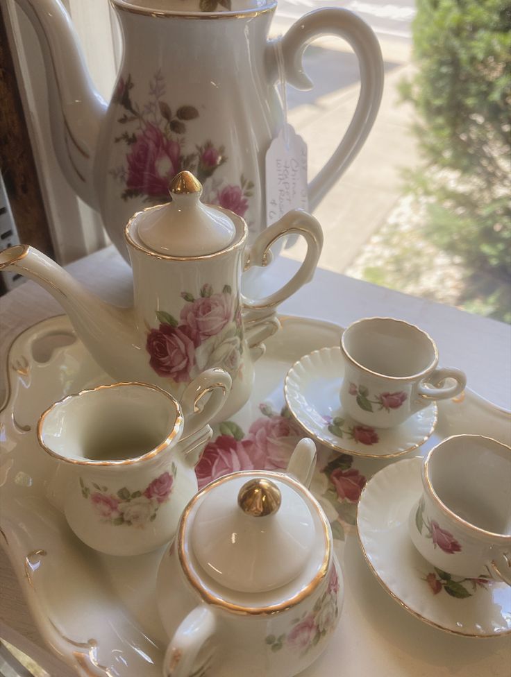 a tea set is sitting on a tray with cups and saucers in front of it