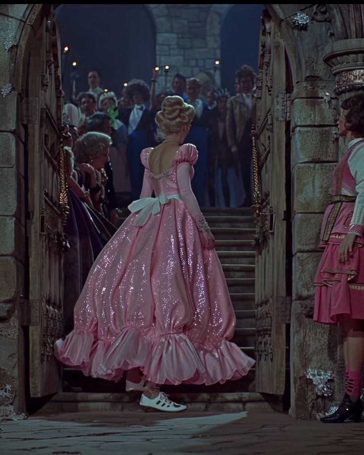 two women in pink dresses standing at the entrance to a castle with lots of people