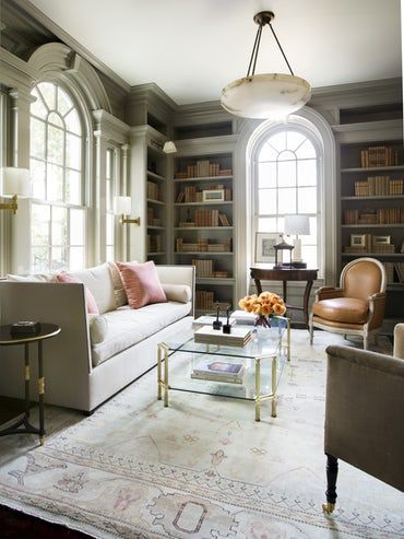 a living room filled with lots of furniture and bookshelves next to a window