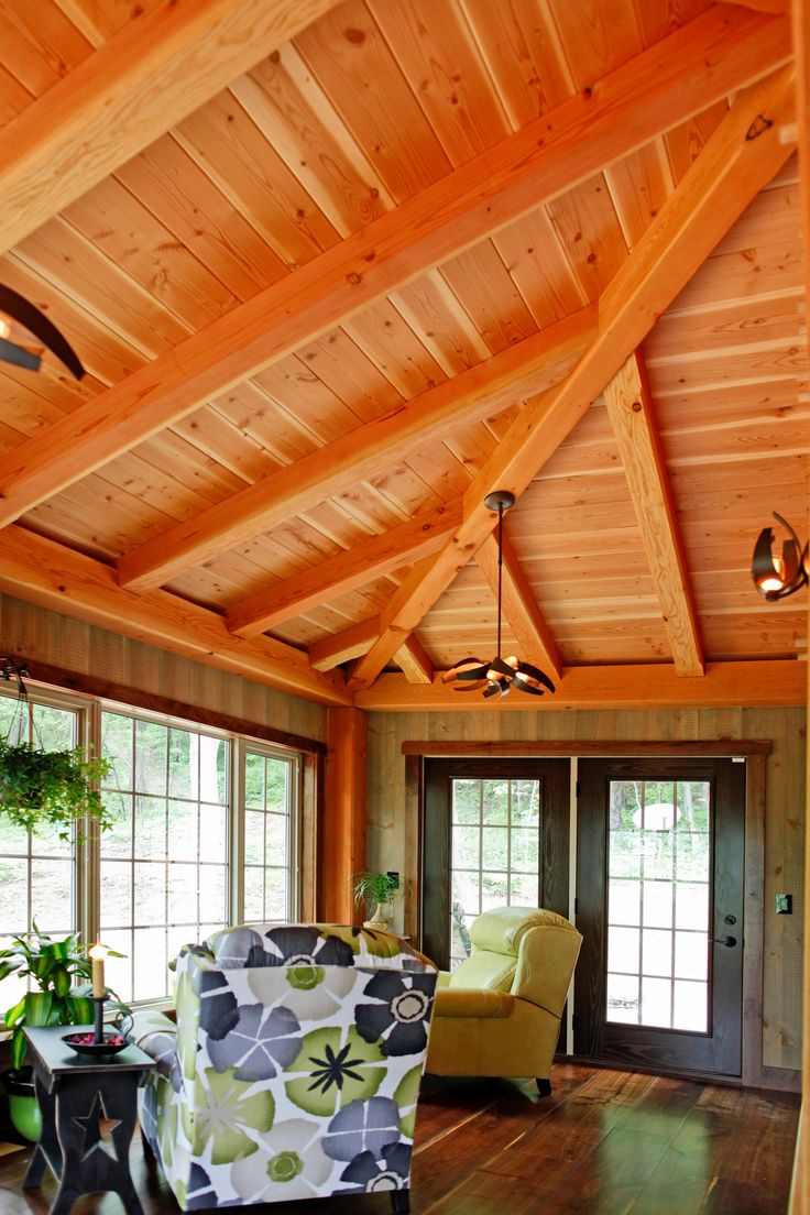 a living room filled with furniture and lots of wooden walls on top of a hard wood floor