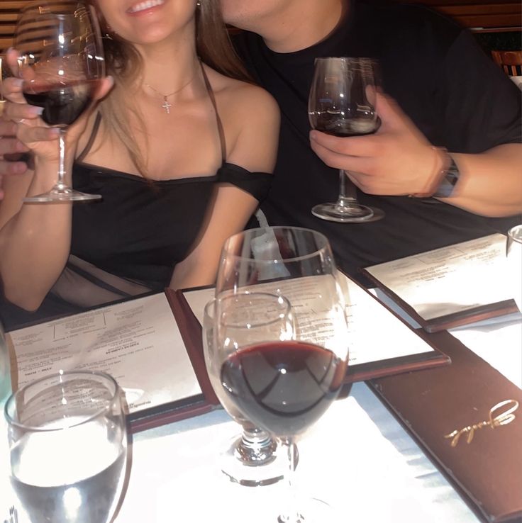 two people sitting at a table with wine glasses