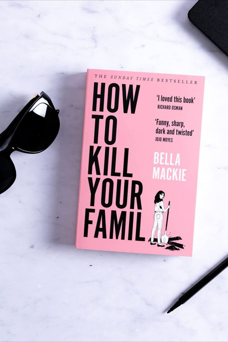 a pink book sitting on top of a white table next to sunglasses and a pen