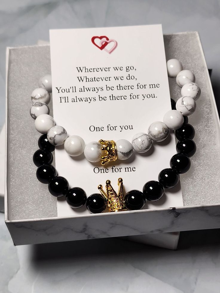 two bracelets with black and white beads in a box on a marble countertop