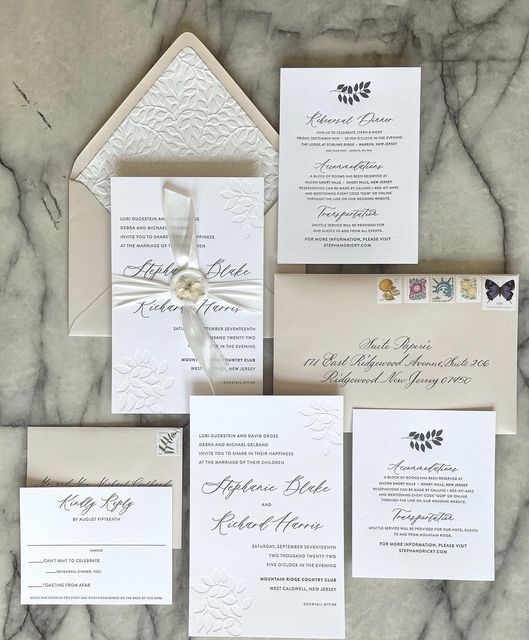 the wedding stationery is laid out on a marble surface