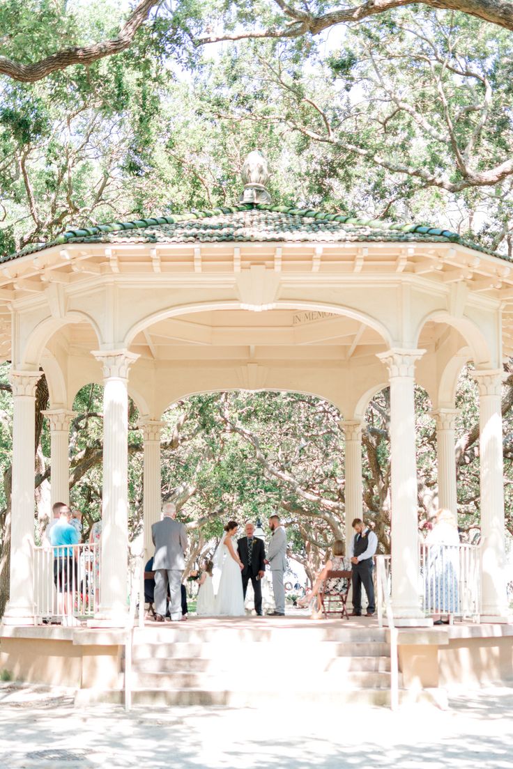 a group of people standing under a white gazebo