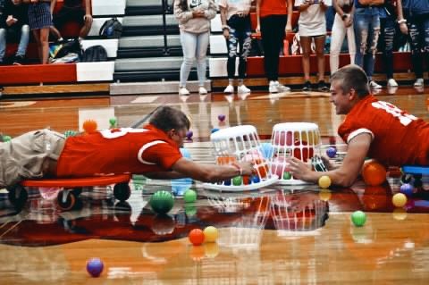 two men laying on the floor with toys in front of them and people standing around