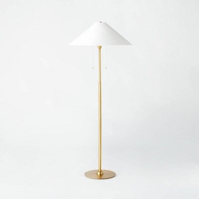 a floor lamp with a white shade on the base and a gold plated base