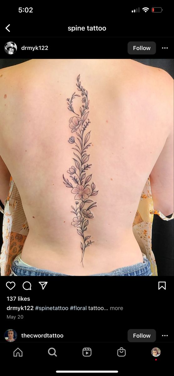 the back of a woman's lower back tattoo with flowers and leaves on it