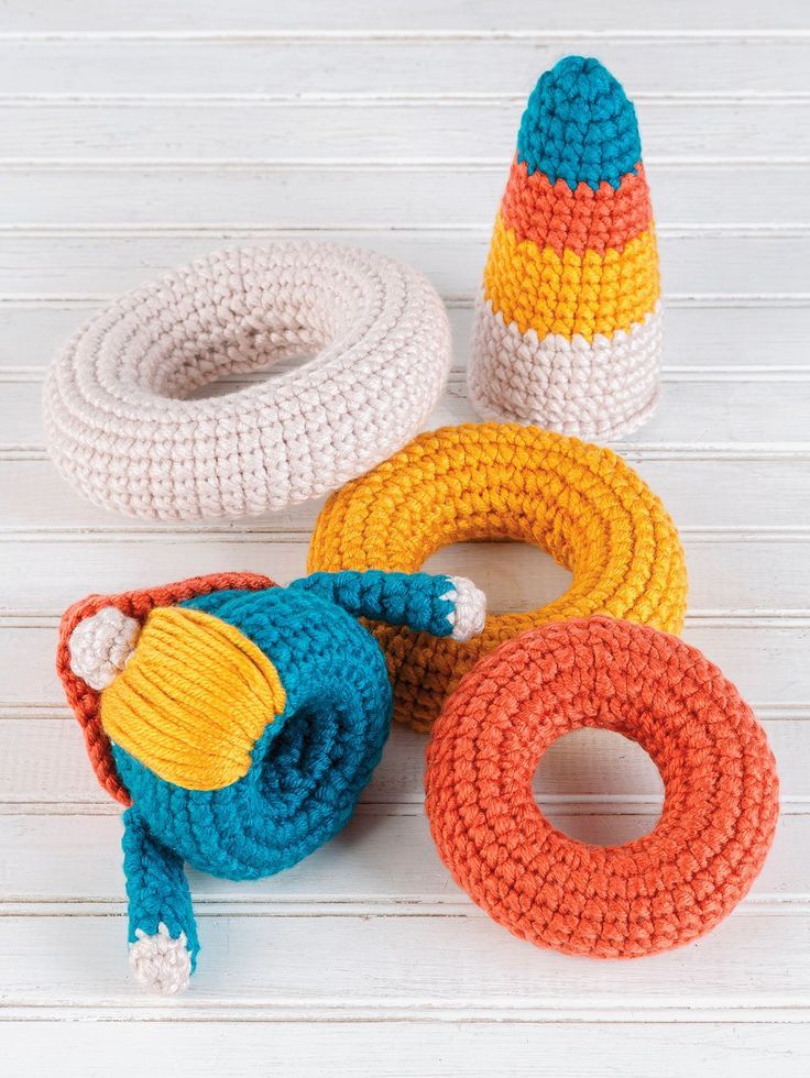 crocheted toys are sitting on a white table with wood planks in the background