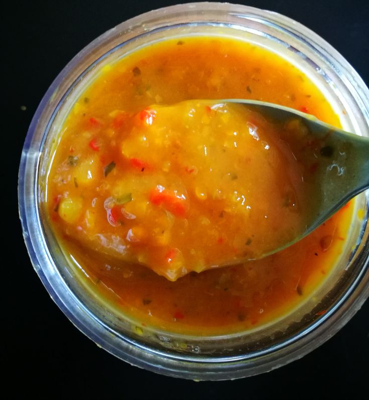 a spoon full of soup sitting in a bowl on top of a black countertop