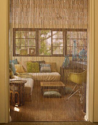 a living room filled with furniture next to a window covered in bamboo blinds and shades