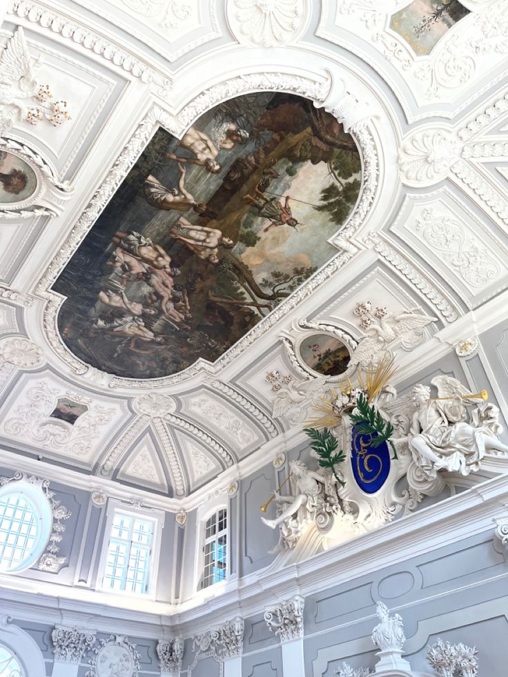 an ornate ceiling with paintings on it in a large white room filled with windows and decorations