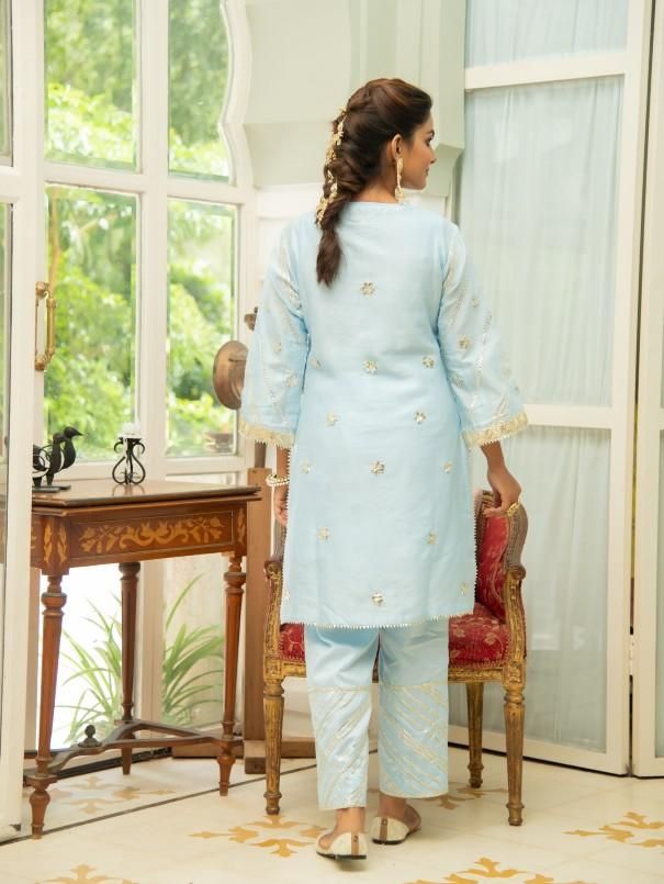 Set of 3 consists of kurta, pant and inner. Noor, bringing the magic of festivities straight to your closet in shades of pastels. Kurta: A elegant powder blue short chanderi kurti with heavy gota lace detailing on the neckline, sleeves & hemline. Comes with an inner. Pants: Straight fit cotton silk pants adorned with gota detailing. Occassion: Day Wear, Evening Wear, Festive Wear Fabric: Chanderi Wash Care Instructions: Dry Clean Only Note: The product will be shipped within 15-20 days of th Festive Wear, Embroidered Neckline, Silk Pants, Kurta Set, Cut Work, Pants Straight, Powder Blue, Festival Wear, Blue Shorts