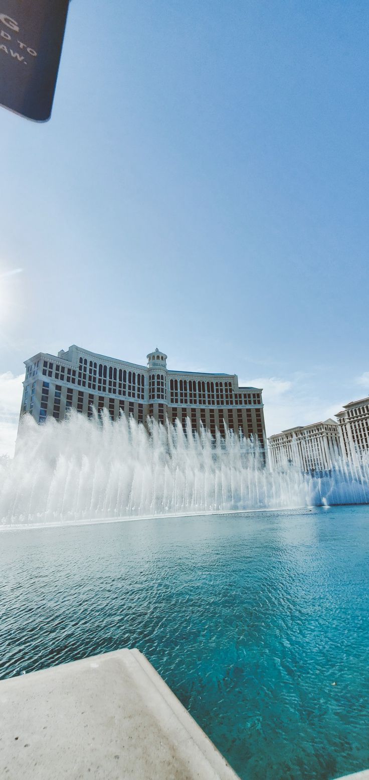 the water is gushing up into the air from the fountains in front of the hotel