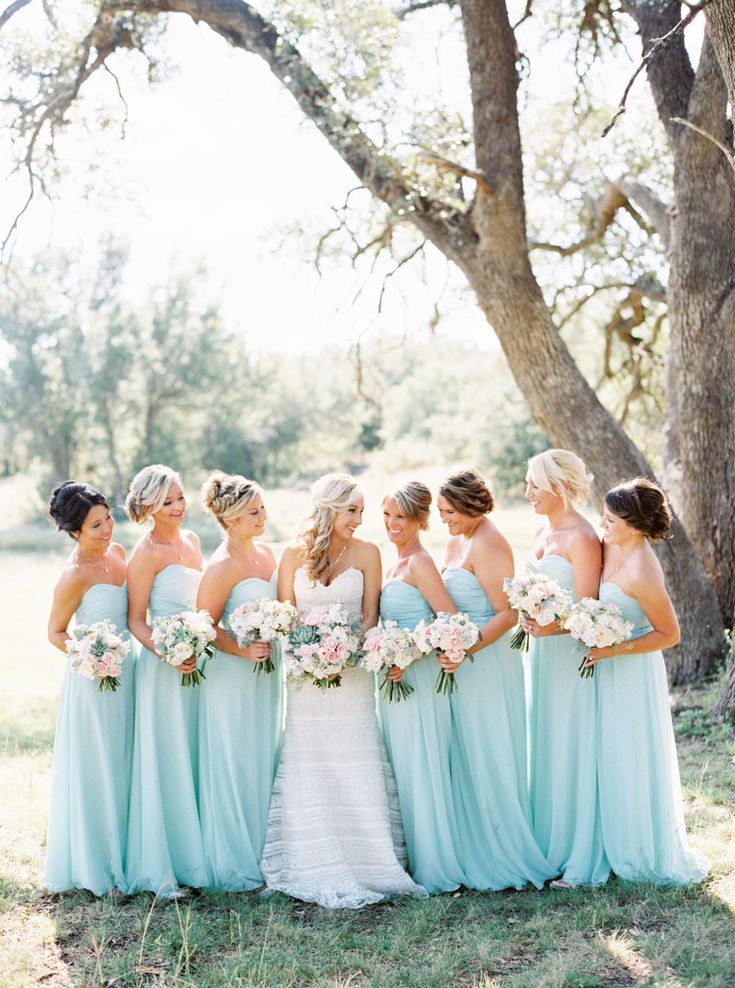 a group of bridesmaids standing in front of a tree