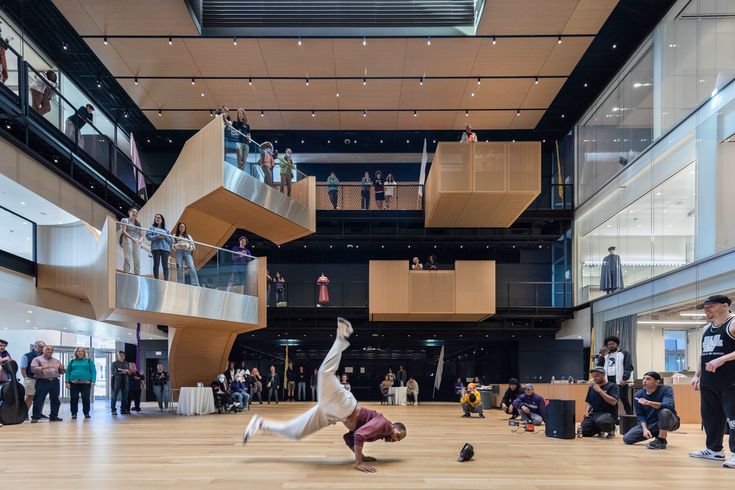 a person doing a handstand on the floor in a large room with many people