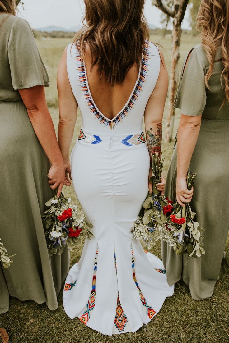 three bridesmaids are standing in the grass with their backs turned to the camera