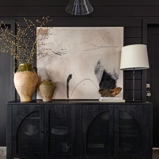 a black cabinet with two vases and a lamp