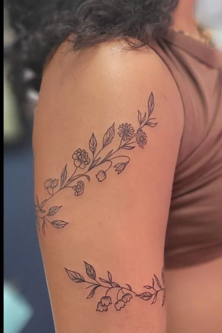 a woman's arm with flowers and leaves tattooed on the back of her shoulder