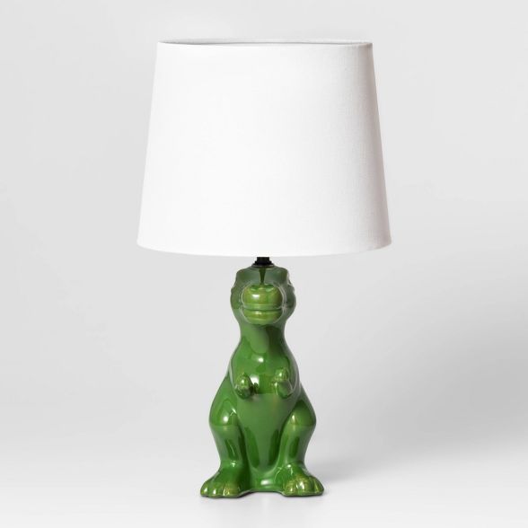 a green ceramic bear lamp sitting on top of a white table next to a white lampshade