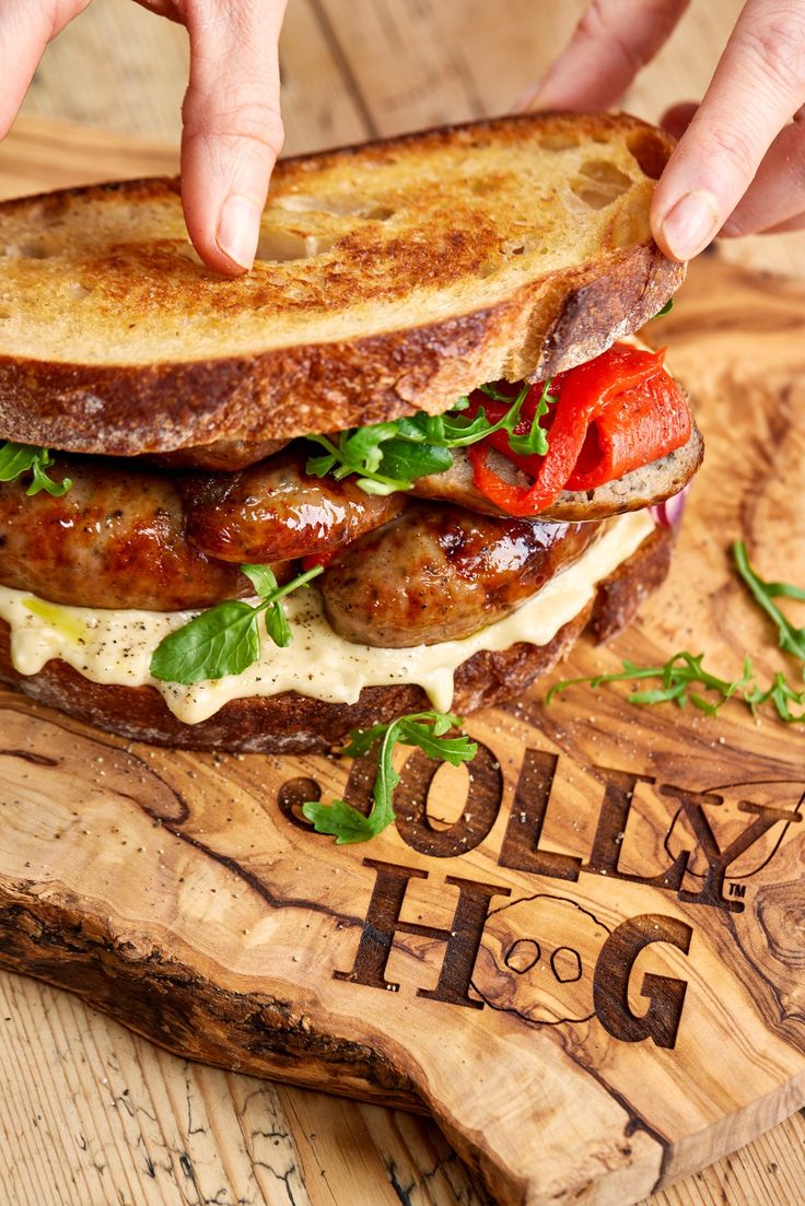 a person reaching for a sandwich on a cutting board