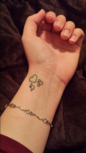 a woman's wrist with a clover tattoo on her left hand and a chain around the wrist