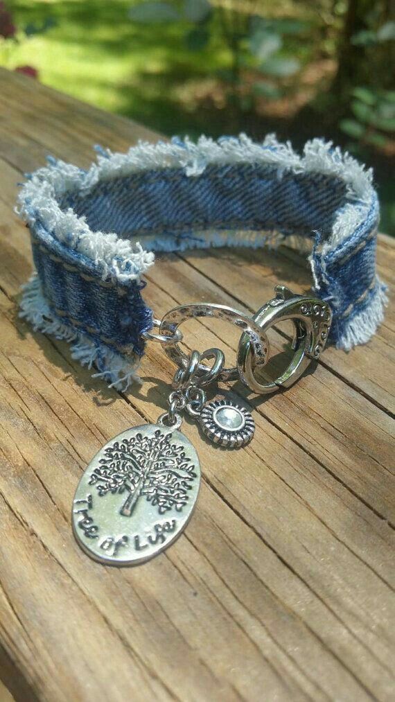 a bracelet with a tree charm on it sitting on top of a wooden table next to flowers