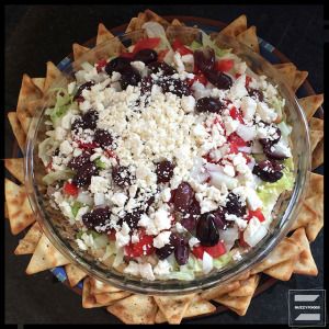 a bowl filled with lots of food on top of a table next to crackers