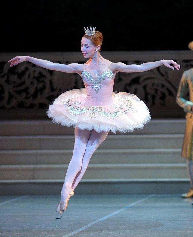 the ballerina is dressed in pink and white