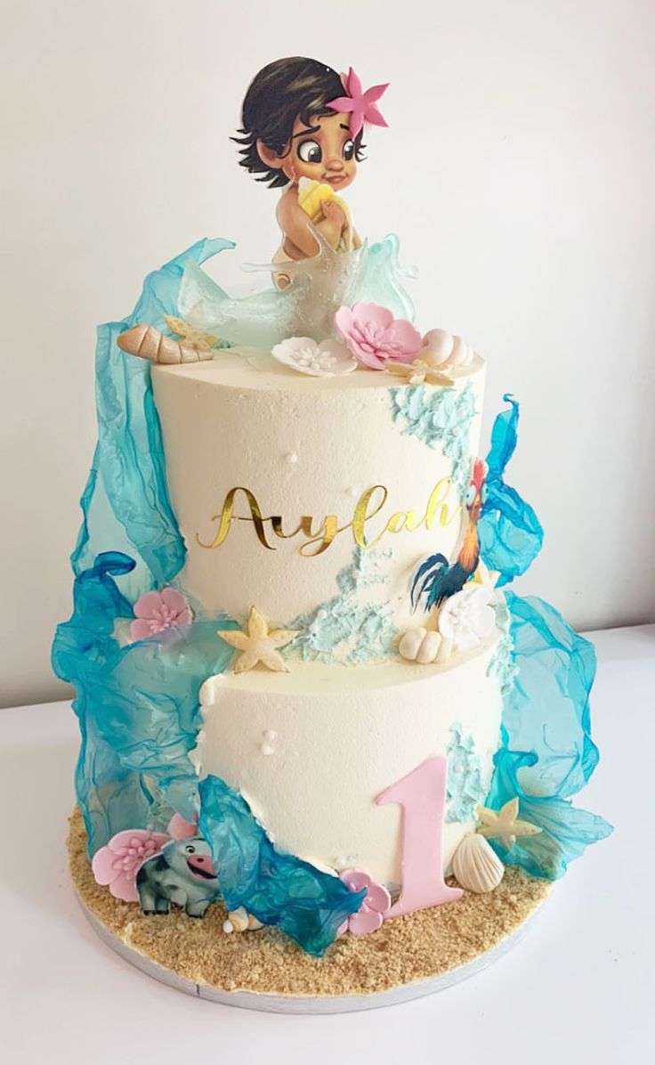 a three tiered cake decorated with an image of a little mermaid on the top