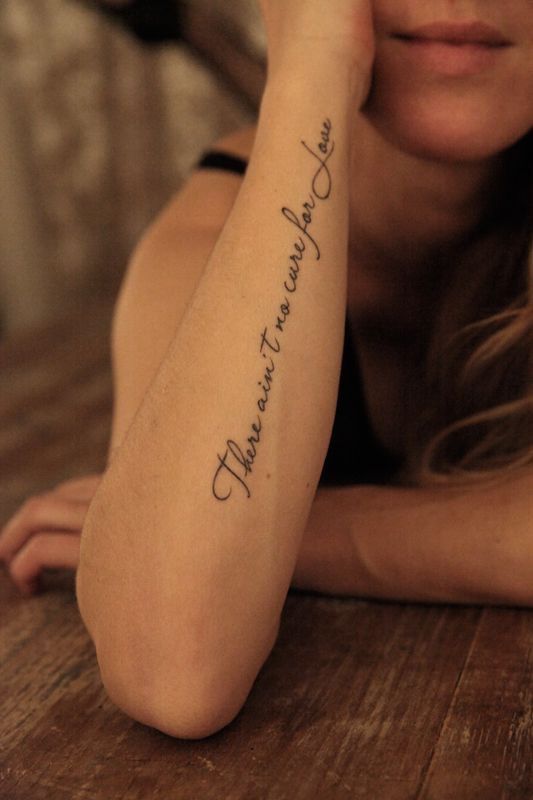 a woman is sitting on the floor with her arm over her head and writing on it