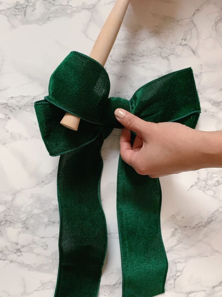 a person is holding a green ribbon with a wooden handle