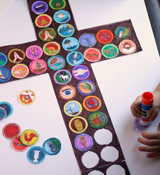 a cross made out of stickers on top of a white table next to markers