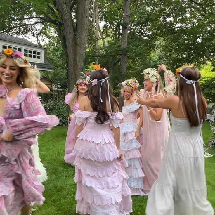 several girls dressed in pink and white dresses are walking through the grass with their arms around each other