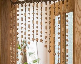 an open window with wooden beads hanging from it's side and a potted plant in the background