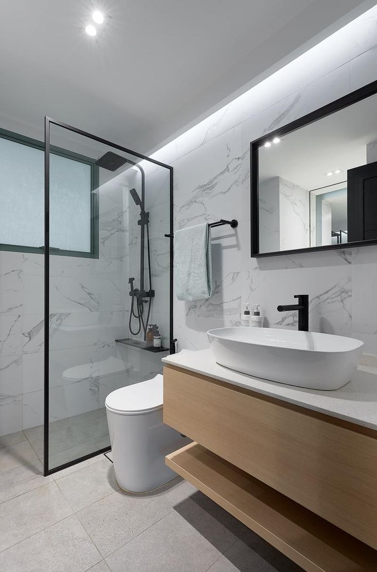 a modern bathroom with white marble walls and flooring, including a large mirror over the toilet