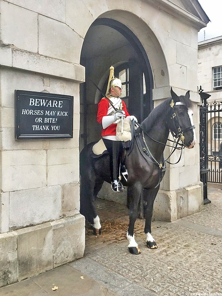 a statue of a man on a horse in front of a building with a sign that says beware horses may block the entrance to thank you