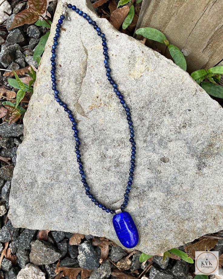 Lapis Gemstone and Blue Glass Necklace Pendant This unique necklace features beads crafted from lapis lazuli, a semi-precious stone prized for its intense blue hue, accented with a cobalt glass pendant. The delicate design showcases the beauty of these blue tones against the wearer's skin in a subtle yet striking manner. Those seeking jewelry that incorporates high-quality natural materials in an understated design will appreciate this singular piece. Details:  - Necklace length: 16 inches - Pen Glass Necklace Pendant, Key Necklace Vintage, Cobalt Glass, Natural Stone Jewelry, Glass Pendant Necklace, Delicate Design, Unique Necklace, Linen Bag, Blue Tones