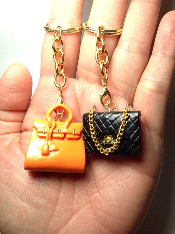 two small purses are being held in someone's hand with chains on them