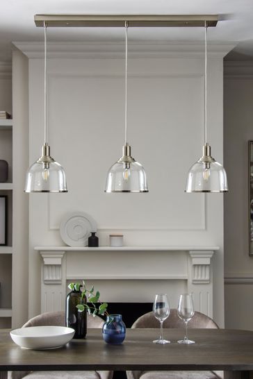 a dining room table with four lights hanging over it