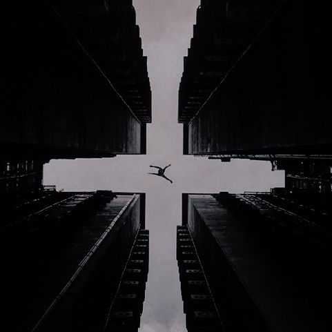 a large cross in the middle of some tall buildings with one person standing on it