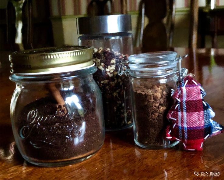 three glass jars filled with dirt sitting on top of a wooden table