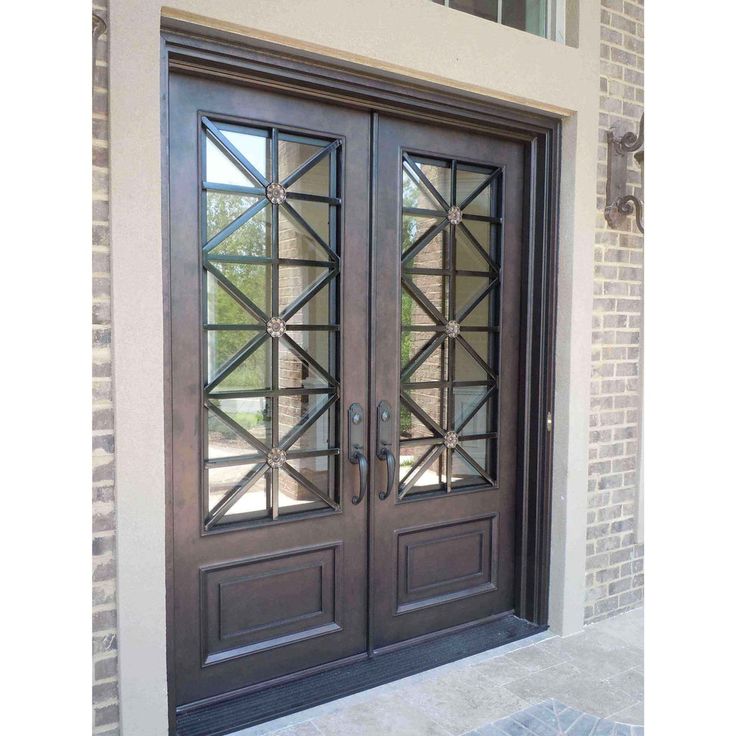 two double doors with glass panels on the side of a brick building, one is dark brown and the other is light brown