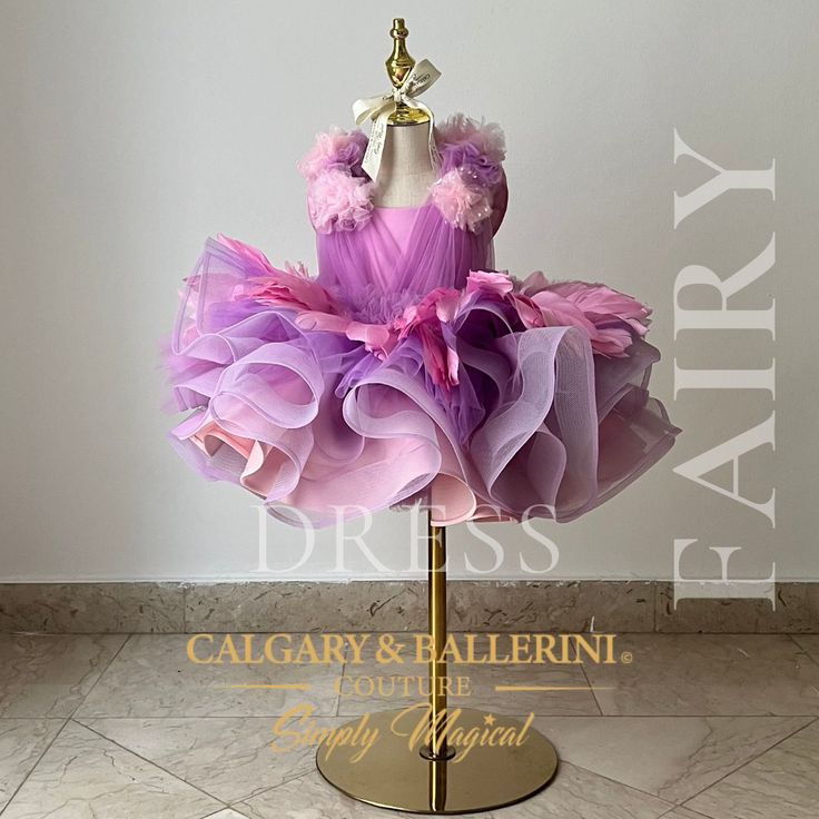 a mannequin dress with ruffles and bows sits on a gold stand