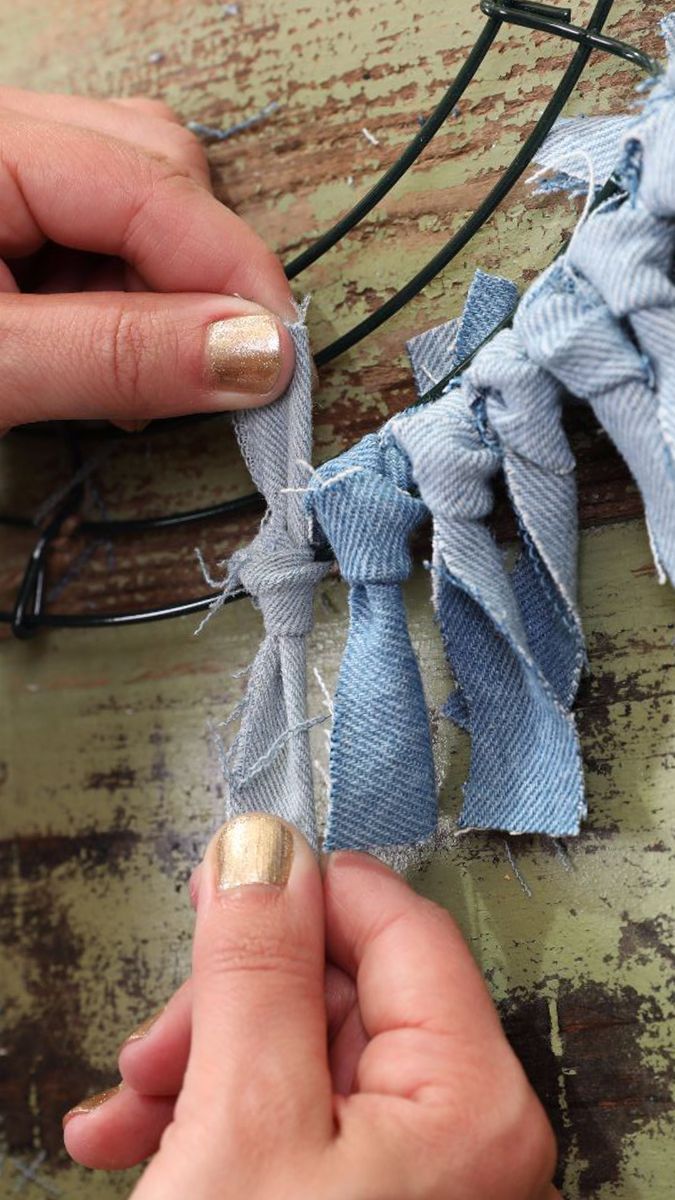 someone is working on some fabric with scissors and thread in their hands while another person holds the string