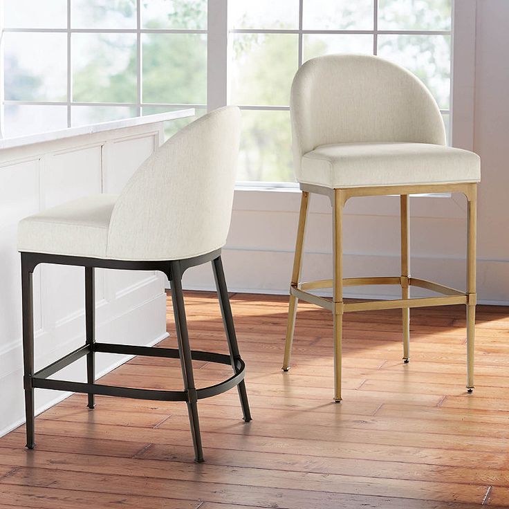 two white chairs sitting next to each other on top of a hard wood floor in front of a window