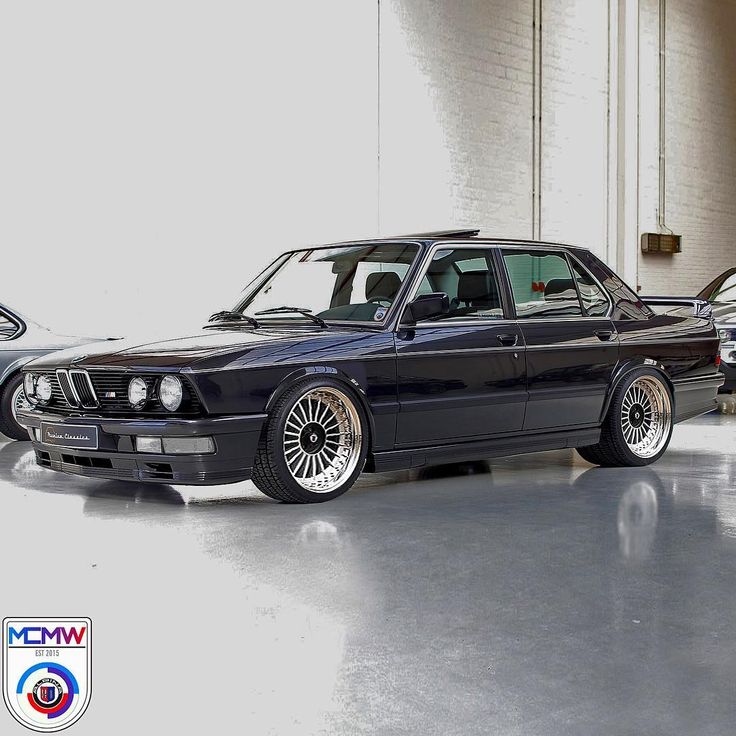 a black car parked in a garage next to another car with chrome rims on it