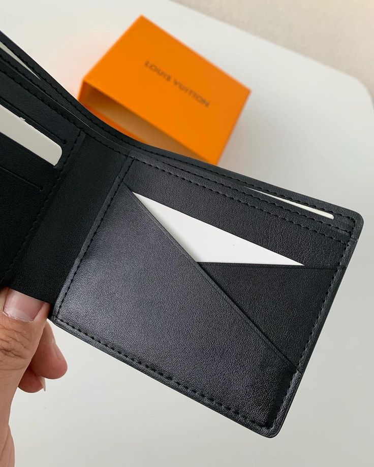 Embrace sleek sophistication with this minimalist wallet, inspired by the iconic Louis Vuitton design. Crafted from premium black leather with a subtle-grained texture, it exudes understated luxury. The signature LV emblem in a matching tonal finish adds a discreet touch of branding. Its slim profile and practical design make it a perfect everyday companion for the modern minimalist. Modern Black Wallets For Business, Modern Black Business Wallets, Luxury Black Trifold Wallet For Formal Occasions, Modern Black Wallets With Card Slots, Modern Black Wallets With Interior Card Slots, Modern Black Wallet With Interior Card Slots, Luxury Black Wallets With Coin Pocket, Luxury Black Wallet With Coin Pocket, Luxury Black Trifold Wallet With Coin Pocket