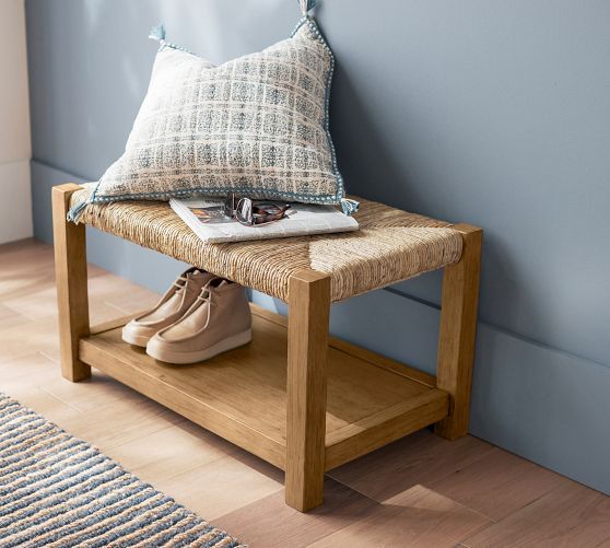 a pair of shoes sitting on top of a wooden bench next to a pillow and rug