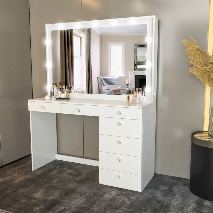 a white dressing table with lights on it and a mirror over the top that is lit up